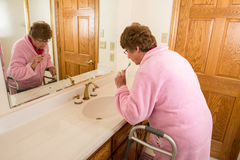 elderly-senior-woman-brushing-teeth-her-medical-aid-walker-her-bathroom-assisted-living-nursing-home-concept-64290289